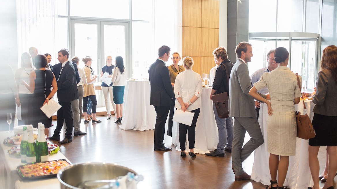 event-staff-member-handing-out-ID / conference-attendees-socializing-during-lunch-break